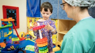 A medical professional watches a young patient play with a toy.
