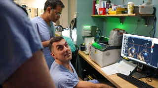 Two surgeons look on at a computer screen.