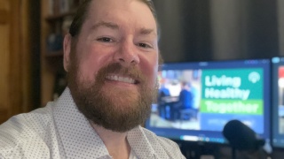 Podcast host Phil Rau poses before his podcast microphone.