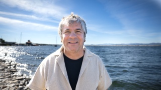 Chris Lazar stands on the shoreline posing for a photo.