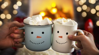 Two snowman face mugs of hot chocolate topped with marshmellows.