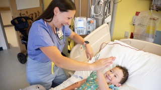Megan Prue, MD, gives a pediatric patient a high five at Golisano Children's Hospital.