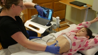 Pediatric patient Macie Hoyt lays on a hospital bed for an ultrasound on her abdomen.