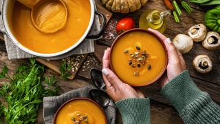 A bowl of curried squash soup with vegetables.