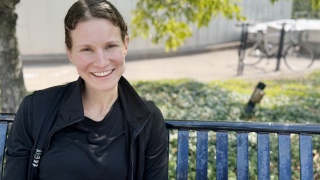 Portrait of Tori Constantine sitting on a bench outside.