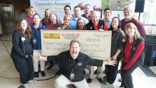Group photo of philanthropy colleagues with a donation check.
