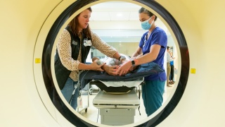 Two providers help a patient during an imaging test.