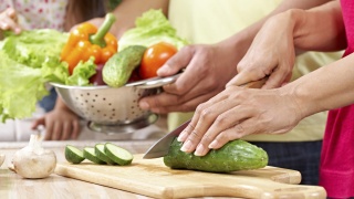 Stock photo of adults cutting vegetables for cooking.