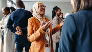 Adult wearing a head scarf or hijab speaks to a group of people.
