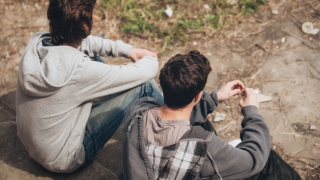 Two men sitting together outside looking away from the camera.