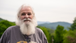 Portrait of John Kohlmeyer standing outside with mountains behind him.