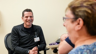 A medical professional smiles and speaks to a patient.