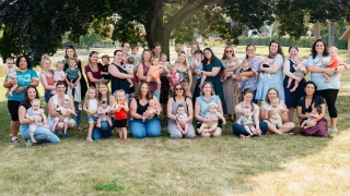 A group of women and their children pose and smile for the camera.
