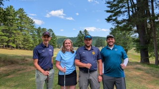 Four golfers smile at the camera.