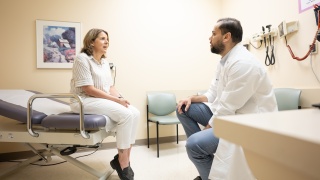 A physician speaks with a patient in a hospital exam room.