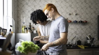 Two young men cook dinner together. 