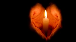 Close-up of a hand holding a lit candle.