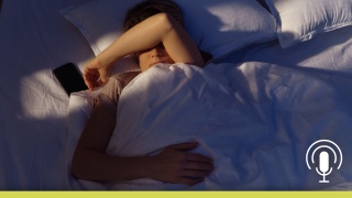A man lying awake in bed with his arm over his face