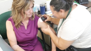 Rochelle Paquette, DNP doing a skin cancer screening check on a patient