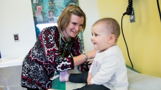 Dr. Jessica Heath smiles as she examines a toddler in a pediatric exam room.