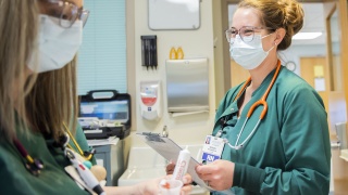 A female travel nurse smiles while working at the hospital.