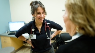 Dr. Marie Sandoval talks with female patient in an exam room.