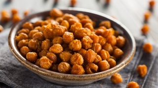 Healthy snack of roasted seasoned chick peas sits on table.