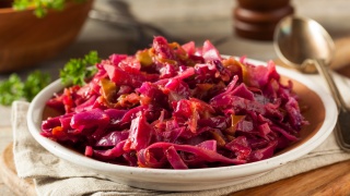 A bowl of cider braised cabbage and apples sits on a table.