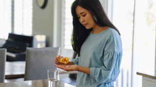 A woman takes prescription antibiotic medication from pill bottle.