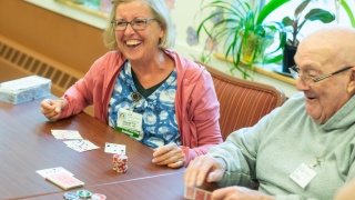 A Home Health and Hospice nurse plays poker with an adult male patient.