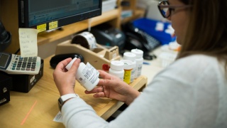 Closeup photo of a pharmacy employee examining prescription bottle