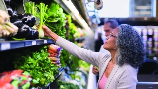 Adult woman buys vegetable at grocery store