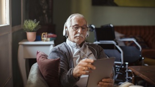 A senior man uses a tablet at home.