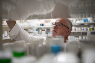 A pharmacist looks through prescription medicine bottles.