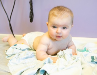 A baby lies on tummy on an examination table. 