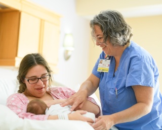 A medical provider offers breastfeeding support to a mother and her baby.