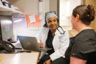 Two medical providers smile at one another.