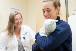 A medical provider looks on as a mother holds her infant.