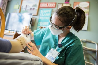 A nurse signs a cast on a patient's foot.