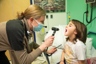 A University of Vermont Medical Center Ear, Nose and Throat provider examines a childs throat.