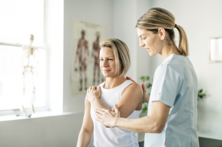 A medical professional helps a patient stretch their elbow.