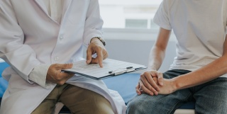 Close-up of the bodies of a medical provider and a patient sitting down for a discussion.