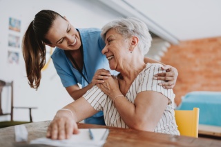 A medical provider embraces a patient by putting her arms on her shoulder.