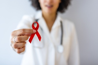 A medical provider holds up red ribbon.