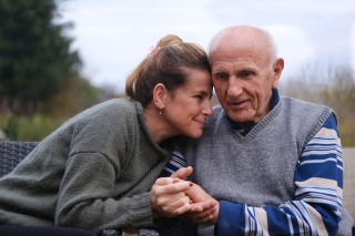 Two adults hold hands while sitting on a bench.