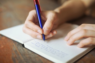 Stock photo of person writing in a notebook.