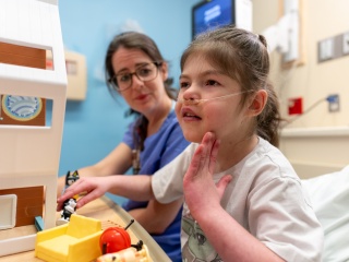 Child patient plays with toys in hospital bed.