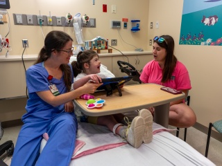 Mother and child talk with Child Life specialist before medical procedure.