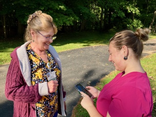 Sheila Kleptz and Amber Doyle, LNAs with Home Health & Hospice, look at a phone.