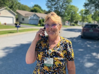 Sheila Kleptz, an LNA with Home Health & Hospice, talks on the phone outside.